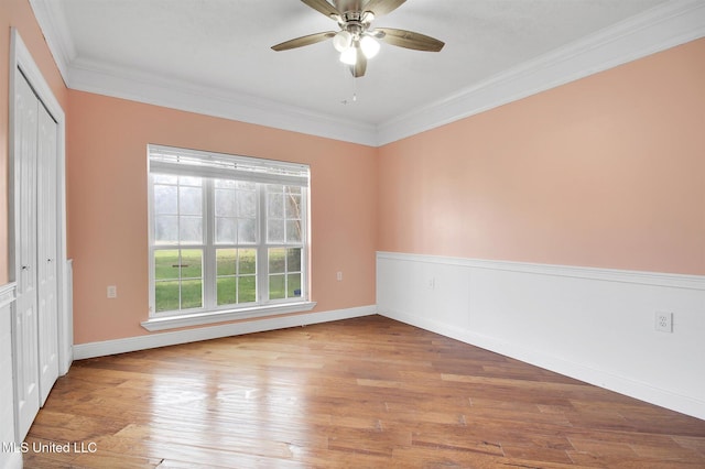 empty room featuring ceiling fan, light wood-type flooring, and ornamental molding