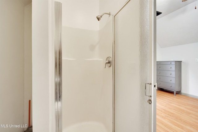 bathroom with vaulted ceiling, an enclosed shower, and hardwood / wood-style flooring