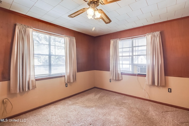 carpeted empty room with cooling unit, ceiling fan, crown molding, and wood walls