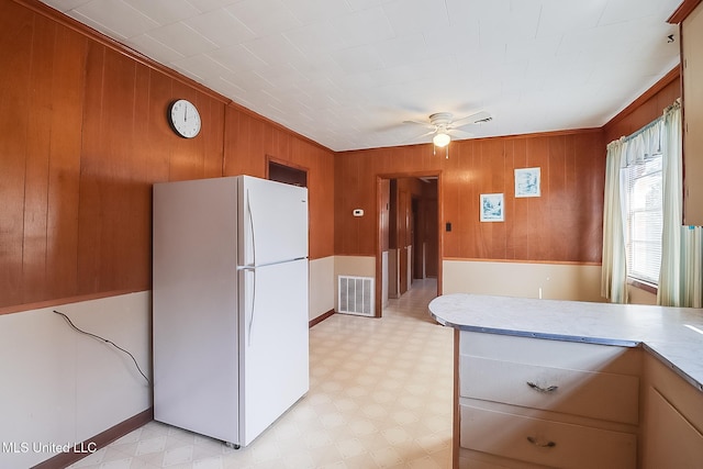 kitchen featuring wood walls, ceiling fan, and white refrigerator