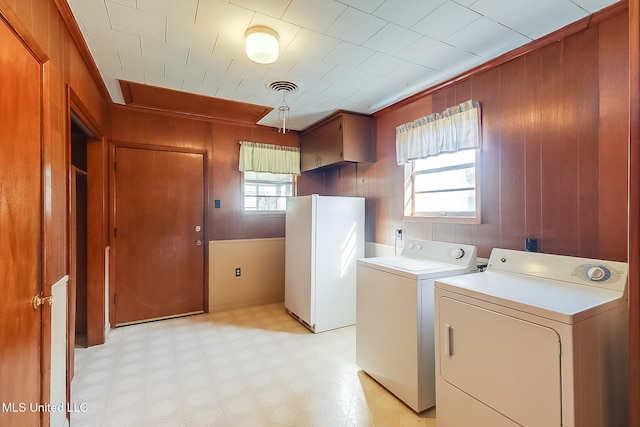 washroom with wood walls, a healthy amount of sunlight, and separate washer and dryer