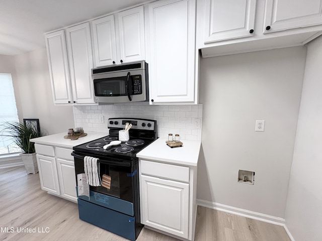 106 Ole Duke Dr, Brandon, MS 39042 - kitchen featuring range with electric cooktop, stainless steel microwave, light wood-style floors, tasteful backsplash, and white cabinetry
