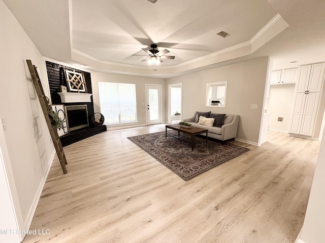 106 Ole Duke Dr, Brandon, MS 39042 - living area featuring a tray ceiling, ornamental molding, ceiling fan, a fireplace with raised hearth, and light wood-type flooring