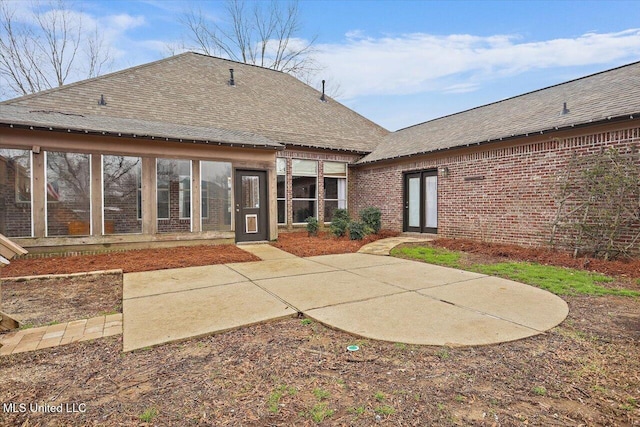 rear view of house featuring a patio area, brick siding, and a shingled roof