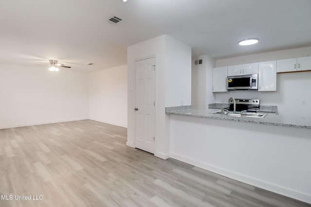 kitchen featuring visible vents, white cabinetry, appliances with stainless steel finishes, light wood-type flooring, and light stone countertops