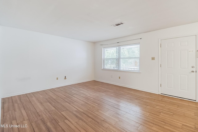 unfurnished room with light wood-style floors, visible vents, and baseboards