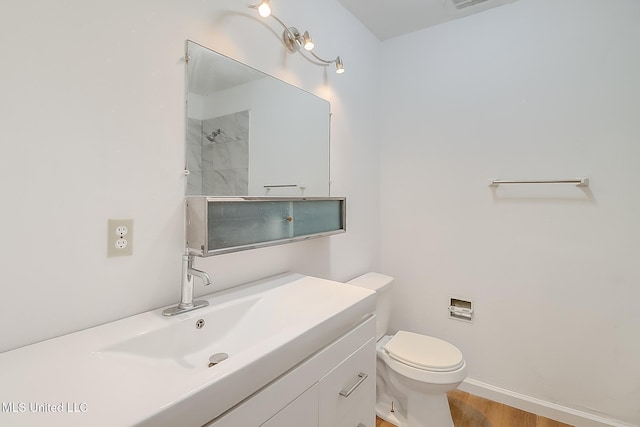 bathroom featuring baseboards, a shower, toilet, wood finished floors, and vanity