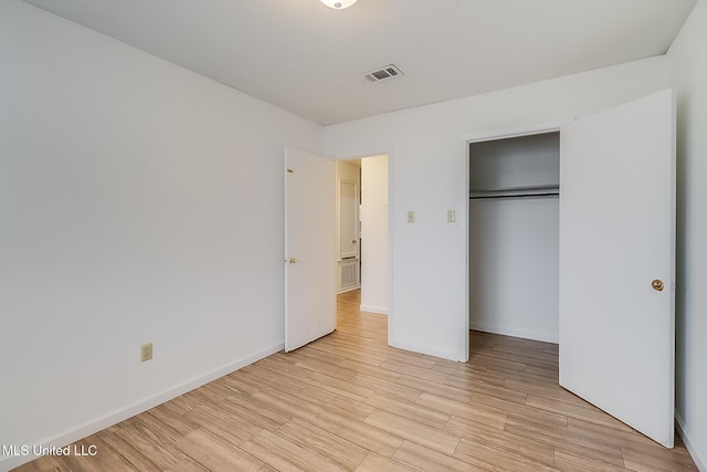 unfurnished bedroom featuring visible vents, a closet, light wood-style flooring, and baseboards