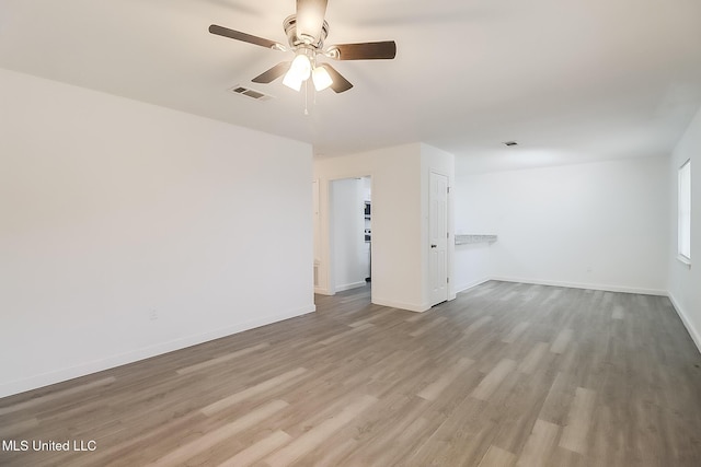 unfurnished room featuring a ceiling fan, baseboards, visible vents, and wood finished floors