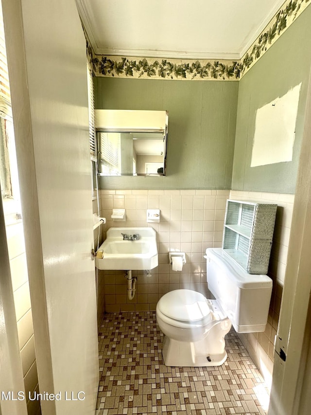 176 Revell Rd, Grenada, MS 38901 - bathroom with toilet, a sink, crown molding, a wainscoted wall, and tile walls