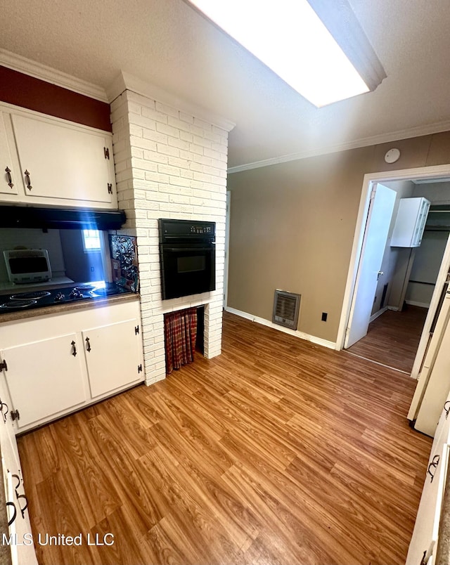 176 Revell Rd, Grenada, MS 38901 - kitchen featuring oven, crown molding, light wood-type flooring, white cabinetry, and baseboards