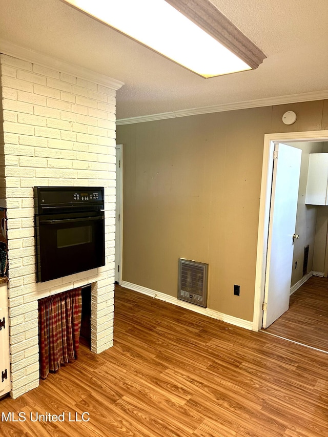 176 Revell Rd, Grenada, MS 38901 - unfurnished living room with crown molding, heating unit, wood finished floors, baseboards, and a textured ceiling