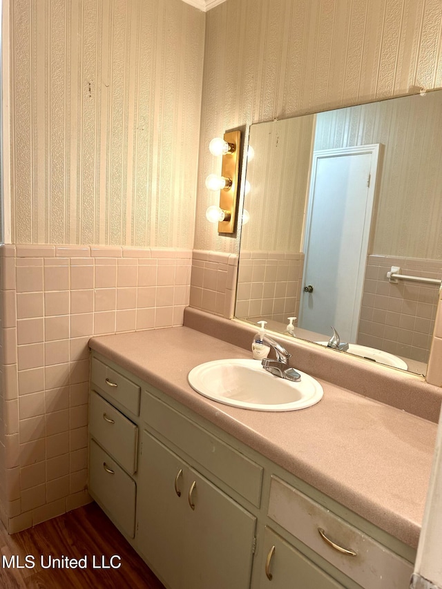 176 Revell Rd, Grenada, MS 38901 - bathroom featuring tile walls, wallpapered walls, vanity, wood finished floors, and a wainscoted wall