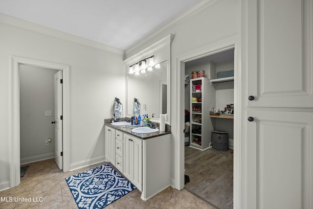 bathroom with double vanity, ornamental molding, a sink, and baseboards