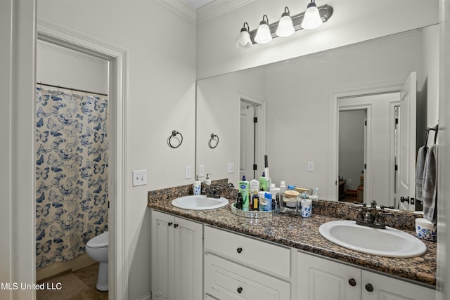 bathroom featuring double vanity, toilet, a sink, and ornamental molding