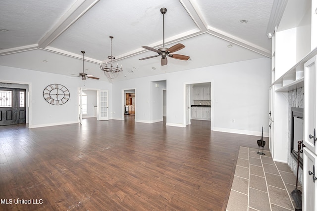 unfurnished living room with dark wood-style floors, beam ceiling, a tiled fireplace, a ceiling fan, and baseboards