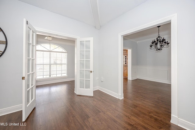 interior space featuring dark wood-type flooring, french doors, a wainscoted wall, and a notable chandelier