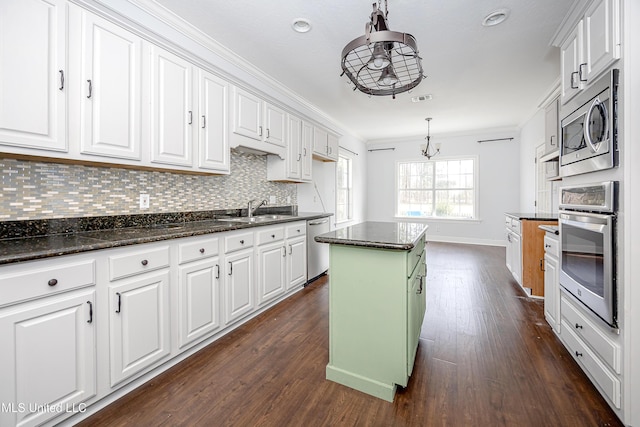 kitchen featuring stainless steel appliances, a sink, a kitchen island, white cabinets, and hanging light fixtures