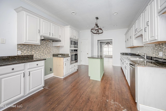 kitchen featuring under cabinet range hood, stainless steel appliances, white cabinets, and decorative light fixtures