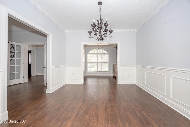 unfurnished dining area featuring a chandelier, dark wood finished floors, crown molding, and wainscoting