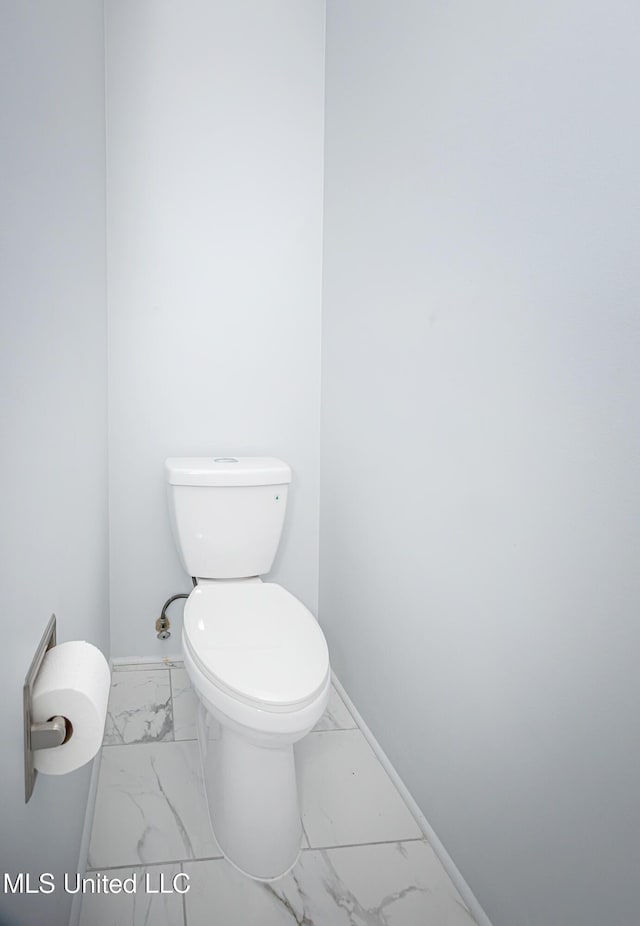 half bath with toilet, marble finish floor, and baseboards