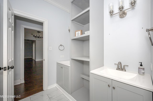 bathroom featuring marble finish floor, baseboards, ornamental molding, and vanity