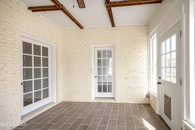 unfurnished sunroom with a ceiling fan and beamed ceiling