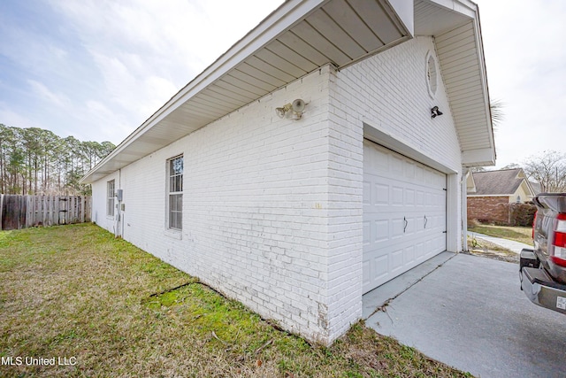 view of side of property with driveway, brick siding, a lawn, and fence