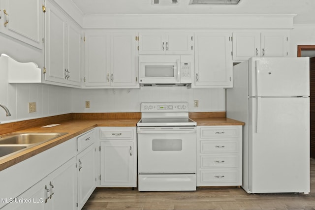 kitchen featuring crown molding, white appliances, wood finished floors, and white cabinets