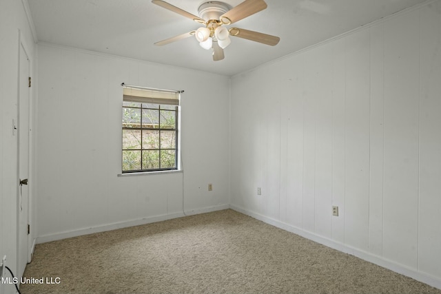 carpeted spare room featuring baseboards, ornamental molding, and a ceiling fan