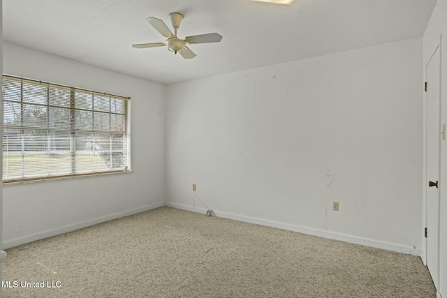 carpeted spare room featuring ceiling fan and baseboards