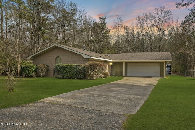 view of front facade with driveway, brick siding, an attached garage, and a yard