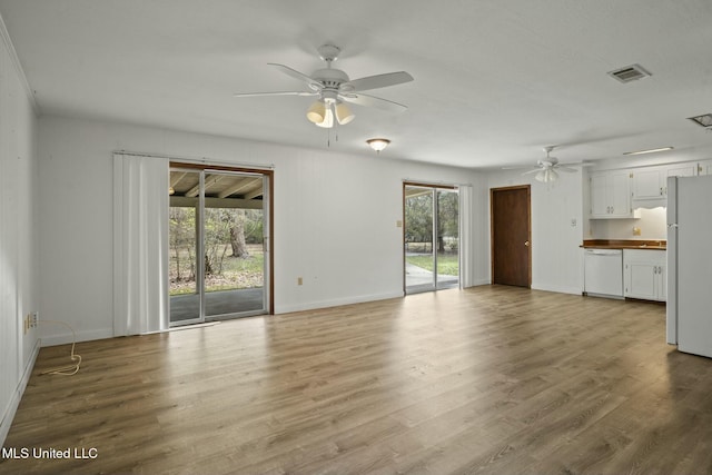 unfurnished living room with a ceiling fan, wood finished floors, visible vents, and a healthy amount of sunlight