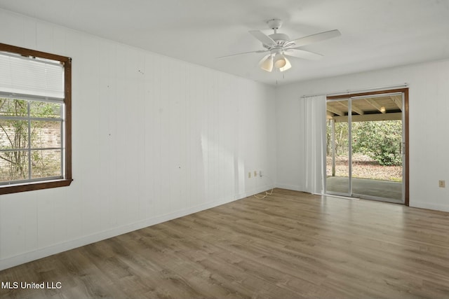 empty room with ceiling fan, wood finished floors, and baseboards