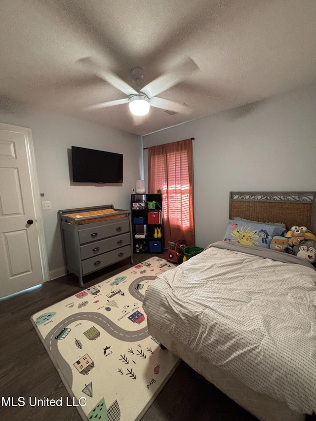 bedroom featuring ceiling fan, dark hardwood / wood-style flooring, and a textured ceiling