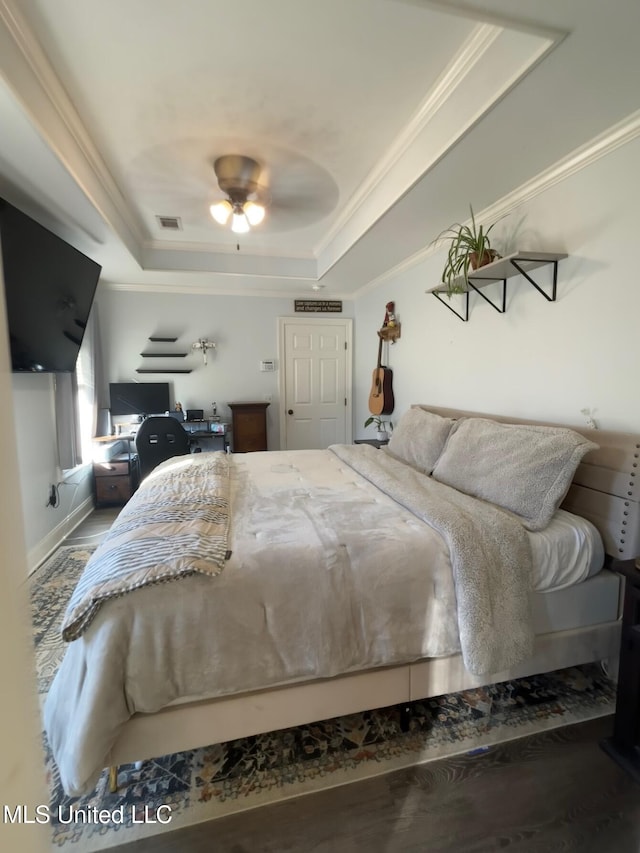 bedroom with hardwood / wood-style floors, ceiling fan, a raised ceiling, and crown molding