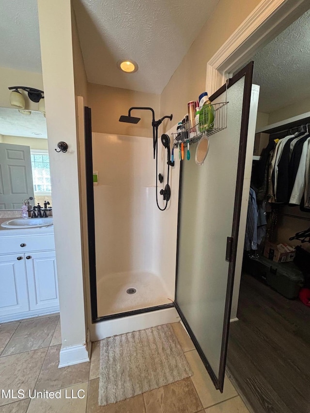 bathroom featuring tile patterned floors, an enclosed shower, and a textured ceiling