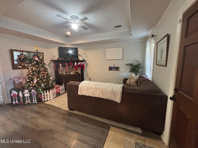 living room with crown molding, hardwood / wood-style floors, ceiling fan, and a textured ceiling