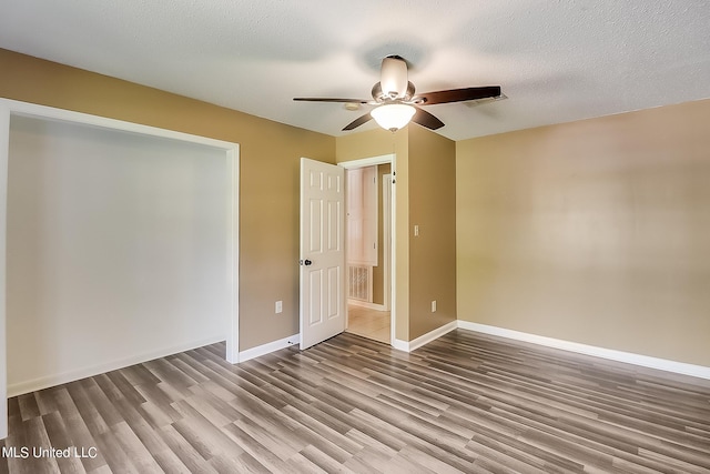 unfurnished room with ceiling fan, wood-type flooring, and a textured ceiling