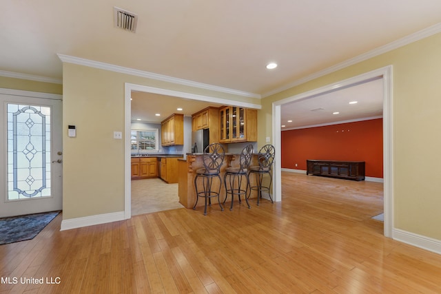 kitchen with kitchen peninsula, a breakfast bar area, stainless steel fridge, crown molding, and light hardwood / wood-style flooring