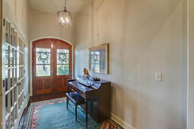 entryway with french doors, dark hardwood / wood-style floors, crown molding, and a notable chandelier