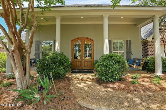 view of exterior entry featuring french doors and covered porch