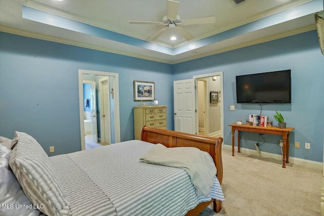 carpeted bedroom featuring crown molding, ensuite bath, ceiling fan, and a tray ceiling