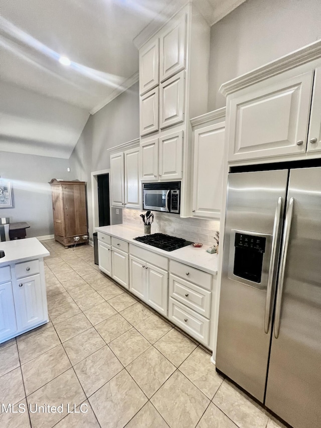 kitchen with light tile patterned floors, white cabinetry, stainless steel appliances, tasteful backsplash, and vaulted ceiling