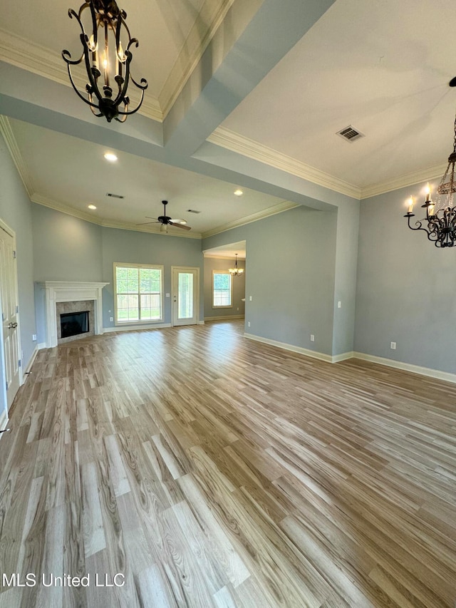 unfurnished living room featuring crown molding, ceiling fan with notable chandelier, and light hardwood / wood-style floors