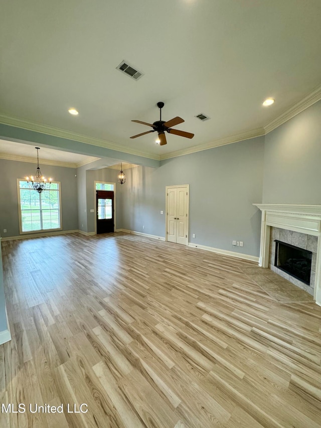 unfurnished living room with ornamental molding, ceiling fan with notable chandelier, a fireplace, and light wood-type flooring