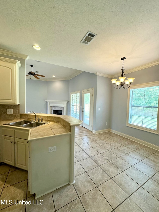 kitchen featuring hanging light fixtures, kitchen peninsula, backsplash, ornamental molding, and sink