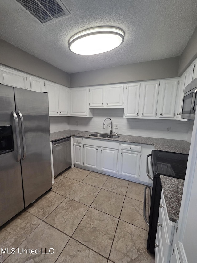 1442 Tally Ho Cir, Gulfport, MS 39507 - kitchen with appliances with stainless steel finishes, a textured ceiling, white cabinetry, and light tile patterned floors