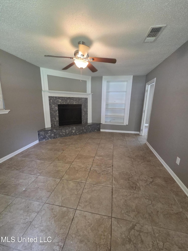 1442 Tally Ho Cir, Gulfport, MS 39507 - unfurnished living room with ceiling fan, a textured ceiling, built in shelves, and a fireplace