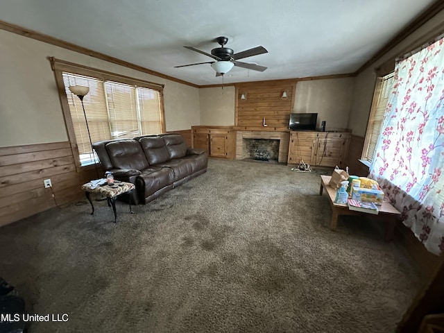 living area with a ceiling fan, wooden walls, carpet floors, a wainscoted wall, and ornamental molding